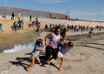 A migrant family, part of a caravan of thousands traveling from Central America to the United States, run away from tear gas in front of the border wall between the U.S. and Mexico in Tijuana, Mexico, November 25, 2018. REUTERS/Kim Kyung-Hoon    SEARCH "POY GLOBAL" FOR FOR THIS STORY. SEARCH "REUTERS POY" FOR ALL BEST OF 2018 PACKAGES. TPX IMAGES OF THE DAY. - RC1C39AE8D30